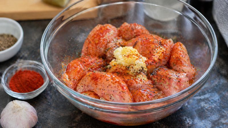 Chicken marination process with spices in bowl